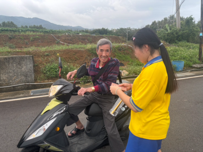 4.豐小妹們攔住一位騎摩托車的阿公，熱情地向他介紹活動的邀請卡。